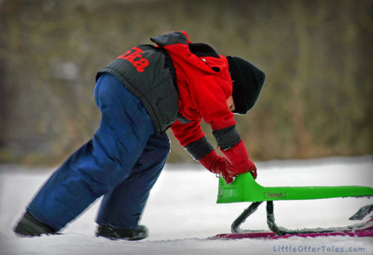 winter play in the snow boy pushing toboggan