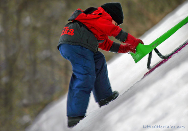 winter play in the snow boy pushing toboggan up hill