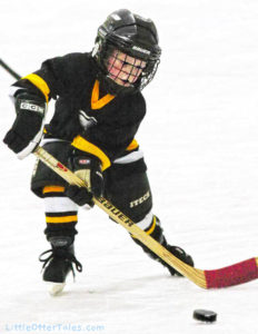 little boy ice hockey player shooting puck