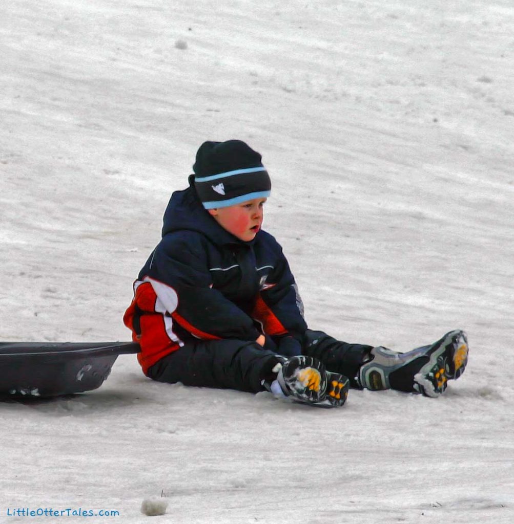 tired boy on sledding hill